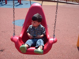 A child swinging on a special safety harness swing at the sensory playground at Fairmount park